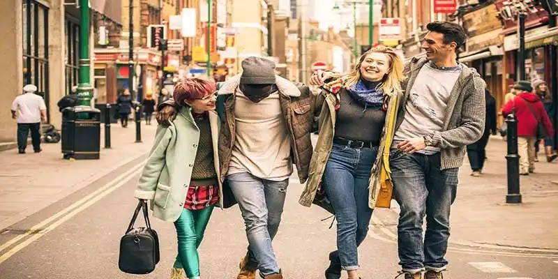 © Mirko - stock.adobe.com | Happy multiracial friends walking on Brick Lane at Shoreditch London - Friendship concept with multicultural young people on winter clothes having fun together - Soft focus with warm contrasted filter