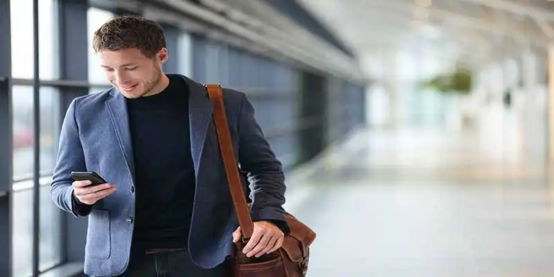 © Maridav - Fotolia | Man on smart phone - young business man in airport