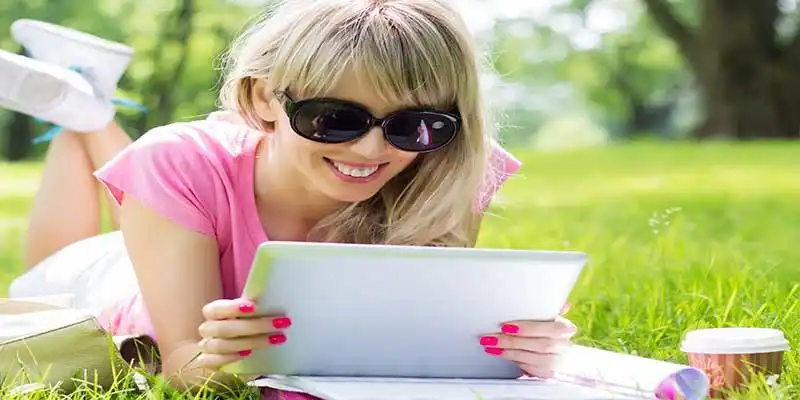 © Kaspars Grinvalds - Fotolia | Happy young woman using digital tablet outdoors in park