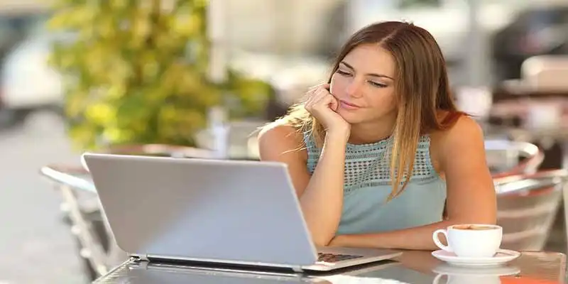 © Antonioguillem - Fotolia | Woman watching a laptop in a restaurant